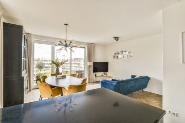 Przestronny, nowoczesny salon z jadalnią i balkonem, gdzie koszty utrzymania nowoczesnego mieszkania są widoczne w wysokiej jakości meblach i wykończeniu.