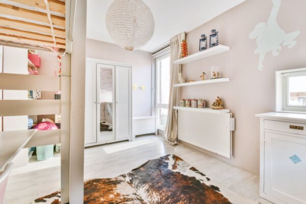 Jasny, przytulny pokój ze skośnymi ścianami i drewnianym sufitem, mogący posłużyć jako inspiracja dla osób szukających porad na temat kupna mieszkania na rynku wtórnym.