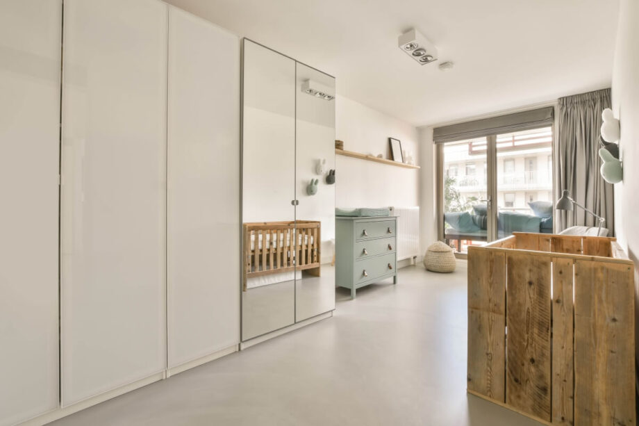 Jasny pokój dziecięcy z drewnianymi meblami i dużym oknem, ilustrujący strategie poszukiwanie idealnego mieszkania.