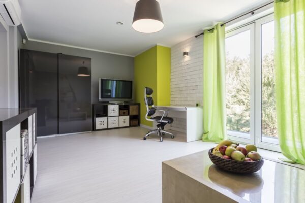 Jasne wnętrze z biurkiem i krzesłem, prezentujące najlepsze nowoczesne mieszkania na wynajem.