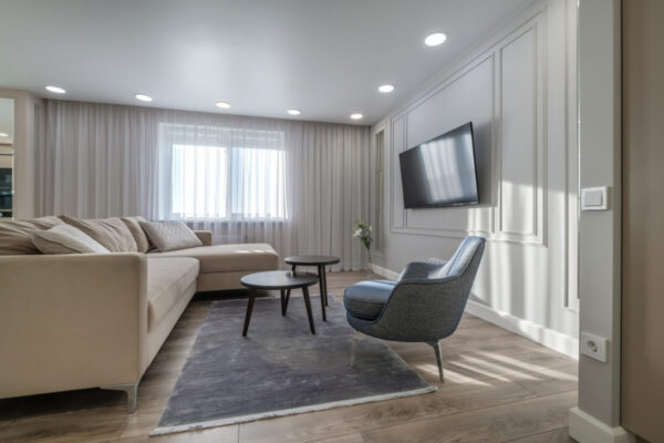 Elegancki salon z jasną sofą i telewizorem, który nasuwa pytania do sprzedawcy mieszkania.
