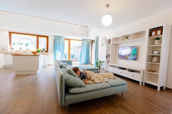 Jasny salon z dużym narożnikiem odzwierciedla najnowsze trendy rynek nieruchomości.